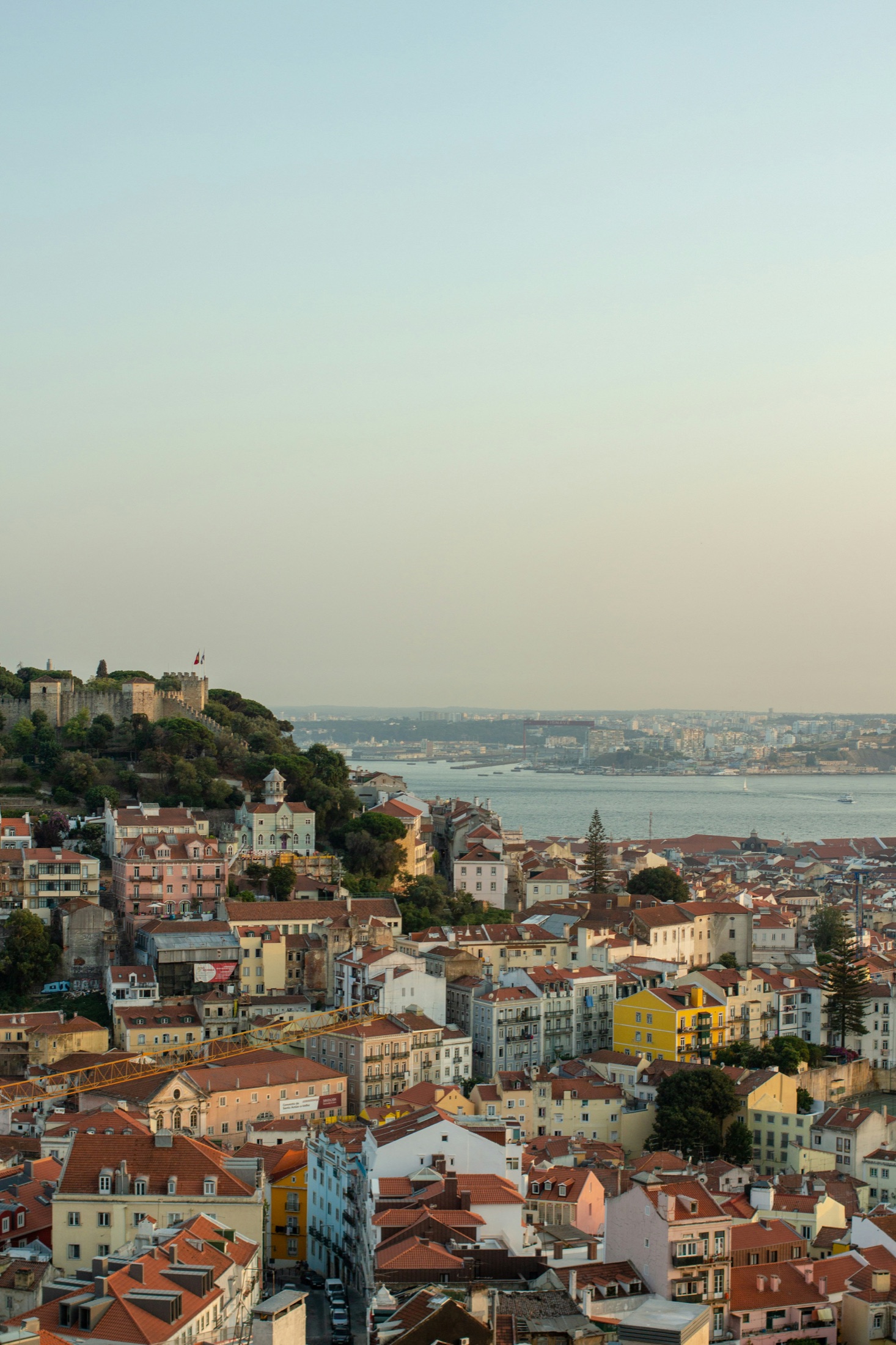 Panoramic view over Lisbon's rooftops and the Tagus river at golden hour, seen from São Jorge Castle